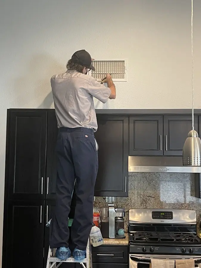 Technician inspecting an air vent during HVAC service in Wayne